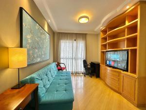 a living room with a blue couch and a tv at Flat luxo, Janela Antirruído, Garagem, serviços in São Paulo