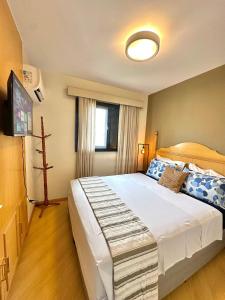 a bedroom with a large bed and a flat screen tv at Flat luxo, Janela Antirruído, Garagem, serviços in São Paulo +37 photos