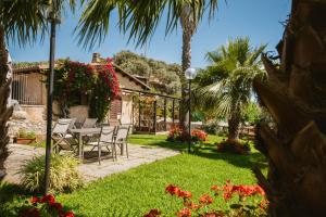 d'une cour avec des chaises et des fleurs. dans l'établissement Calàmi - Villa Romeo - Private Apartments with Pool, Seaview & Olive Grove, à Santa Caterina Dello Ionio Marina