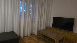 Una sala de estar con un televisor de pantalla plana y una mesa. en Shakespeare Central Apartment, en Craiova 2 fotos más