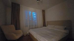 Un dormitorio con una cama, una silla y una ventana en Shakespeare Central Apartment, en Craiova