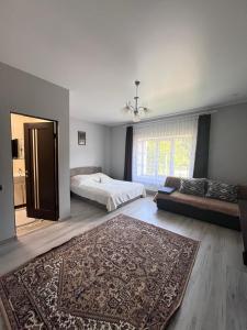 ein Schlafzimmer mit einem Bett, einem Sofa und einem Teppich in der Unterkunft У Лариси in Solotschyn