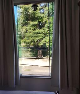 Una ventana del dormitorio con vista a un parque. en Apartamento Moderno com vista para á principal, en Volta Redonda