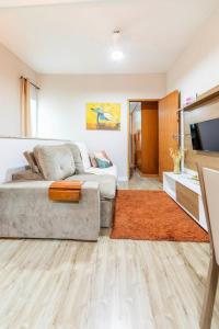 una sala de estar con un sofá y un televisor en Apartamento Moderno com vista para á principal, en Volta Redonda