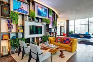 a living room with a yellow couch and chairs at citizenM Miami Worldcenter in Miami