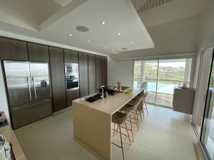 een keuken met een eiland met een wastafel en krukken bij Villa ATA ITI in Punaauia