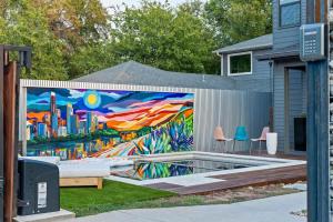 ein Wandgemälde an der Seite eines Zauns mit Stühlen in der Unterkunft Bach & Bubbly House - 5BR, Pool, Gym & Glam Room - Villa in Austin