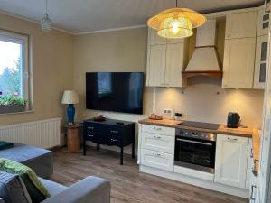 Una cocina con gabinetes blancos y un televisor de pantalla plana. en Apartament Pruszków II, en Pruszków