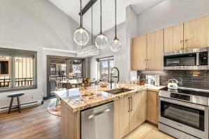 a kitchen with stainless steel appliances and wooden cabinets at Bear Claw 405 - Luxury Condo, Ski-in Ski-out Access, Slope Views & Winter Shuttle! in Steamboat Springs