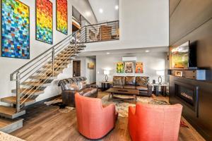 a living room with a staircase and orange chairs at Bear Claw 405 - Luxury Condo, Ski-in Ski-out Access, Slope Views & Winter Shuttle! in Steamboat Springs
