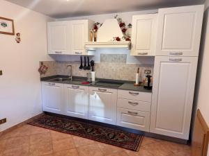 a kitchen with white cabinets and a sink at Dolomites Charme Chalet in Colle Santa Lucia
