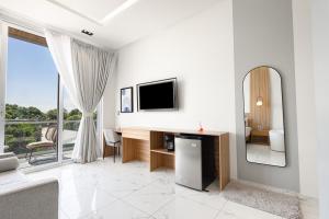 a white living room with a television and a mirror at Hotel H4 Olanchito in Olanchito