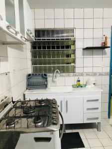 eine weiße Küche mit Herd und Spüle in der Unterkunft Home Confort in Garanhuns