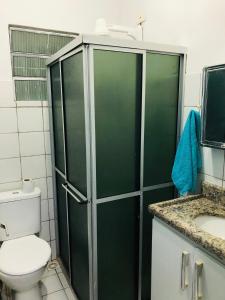 a bathroom with a toilet and a green shower at Home Confort in Garanhuns +13 photos