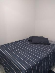 a bed in a room with a blue and white blanket at Home Confort in Garanhuns