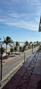 eine leere Straße mit Palmen am Strand in der Unterkunft Apartamento pé na areia, vista para o mar e garagem! in Mongaguá