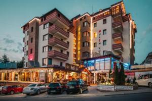 a large building with cars parked in a parking lot at Prime NG Mujen lux & spa in Cajetina