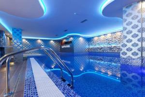 a swimming pool with blue lights in a building at Prime NG Mujen lux & spa in Cajetina