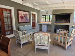 een woonkamer met stoelen, een tafel en een open haard bij Angelierbosch Guest House in Klaarstroom