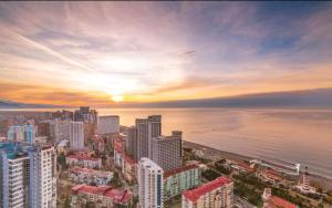 un perfil urbano con la puesta de sol sobre el agua en Panorama Cental Hotel Batumi, en Batumi