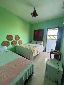 Dos camas en una habitación con paredes verdes. en Pousada Vila Caburé, en Luís Correia