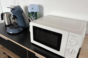 Un microondas blanco sobre una encimera negra. en Bright studio with a view of the Black Forest, en Estrasburgo 16 fotos más