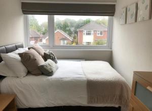 a bedroom with a bed with pillows and a window at Cosy 4 Bed House In Solihull Near Town-NEC-BHX in Sheldon
