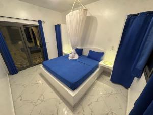 une petite chambre avec un lit bleu et des rideaux bleus dans l'établissement Villa Warang, à Warang