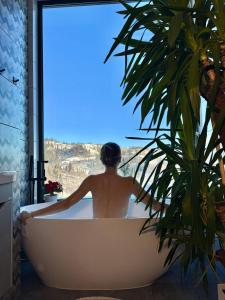 Un hombre sentado en una bañera mirando por una ventana. en Forest Hub, en Slavske