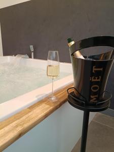 Ein Glas Wein neben einer Badewanne und eine Flasche Champagner. in der Unterkunft Luxus-Apartment Champagner&Strafbock in Herford