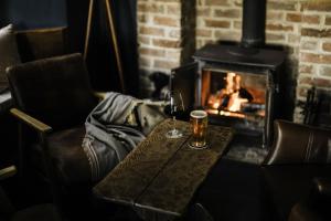 a table with two glasses of wine and a fireplace at Winyard's Gap Inn in South Perrott