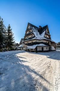 a large building with a snow covered roof on a snow covered slope at Ski Mountain Apartamenty - Plac zabaw - Dmuchaniec - Plac zabaw - Wypożyczalnia rowerów elektrycznych E-Bike Białka in Białka Tatrzańska