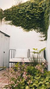 una panchina bianca seduta accanto a un muro con l'edera di Departamento Constitución a Tandil