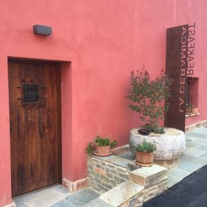 a red building with a wooden door and potted plants at B&B La Ceramica Moline in Vicoforte
