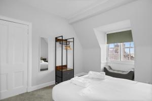 a white bedroom with two beds and a window at Lochside Apt, D in Angus