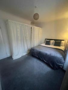 a bedroom with a bed and a window with white curtains at Fairy Cove Cottage in Paignton +14 photos