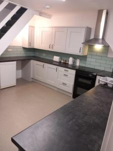 a kitchen with white cabinets and black appliances at Fairy Cove Cottage in Paignton