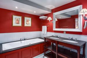 Baño rojo con 2 lavabos y bañera en NH Brugge, en Brujas