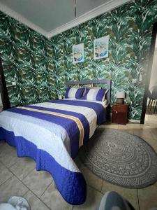 a bedroom with a bed with blue and white sheets and green wallpaper at Wharf 303 in Pointe-Noire