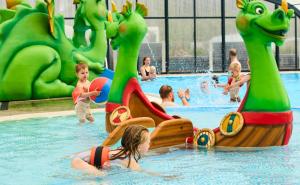 Husodde Strand Camping & Cottages في هورسنز: مجموعة من الأطفال يلعبون في المسبح في الحديقة المائية