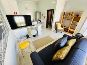 een woonkamer met een blauwe bank en een flatscreen-tv bij Casa do Omega do Foz in Foz do Arelho