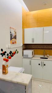 una cucina con mobili bianchi e un vaso con la frutta di شقق ميد كانتري a Khamis Mushayt