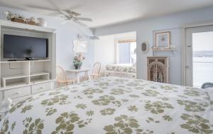 a white bedroom with a bed and a tv at Coastal Garden - Anchor Pier Lodge in Newport
