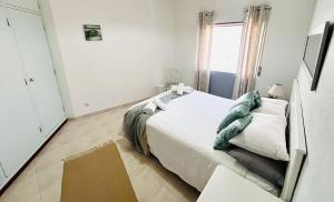 een witte slaapkamer met een bed en een raam bij Casa do Omega do Foz in Foz do Arelho +2 foto's