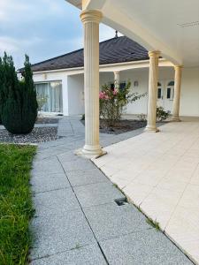 ein großes Haus mit Säulen und einer Terrasse in der Unterkunft Sweet Escape - Studio privé proche du lac du Der in Frignicourt