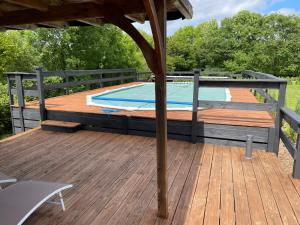 a wooden deck with a swimming pool with an umbrella at Georgie et Margot - Chambres d'hotes et Gite in La Châtre-Langlin