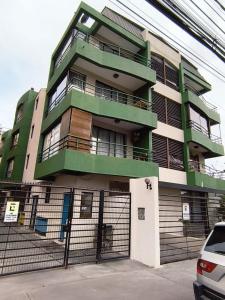 伊基克Departamento a metros de playa Cavancha的绿色和白色的建筑,设有围栏