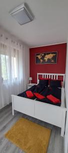 IHB-Inter House of Balaton في زاماردي: غرفة نوم بسرير ابيض بجدار احمر