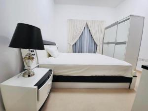 a bedroom with a bed and a lamp on a night stand at Ajman holiday home in Ajman 