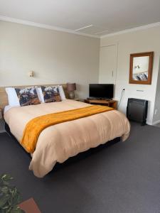 a bedroom with a large bed and a flat screen tv at Lumsden Motel in Lumsden